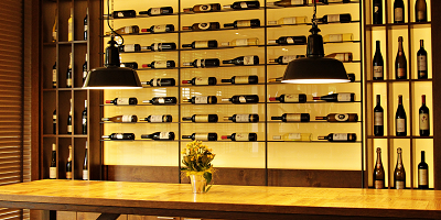 Racks of wine against back wall laying on sides, and bench table at front