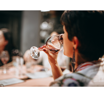 wman drinking red wine at dinner table with family